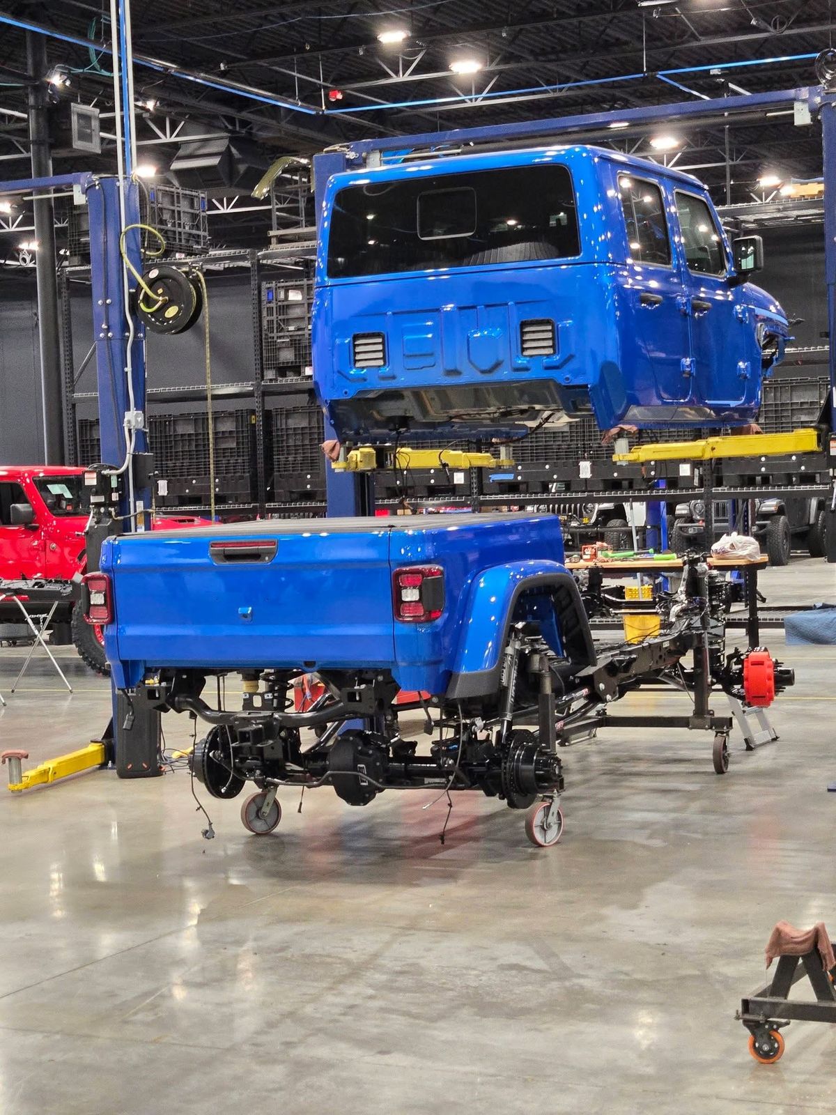 A blue Jeep Gladiator body lifted off its frame during a build