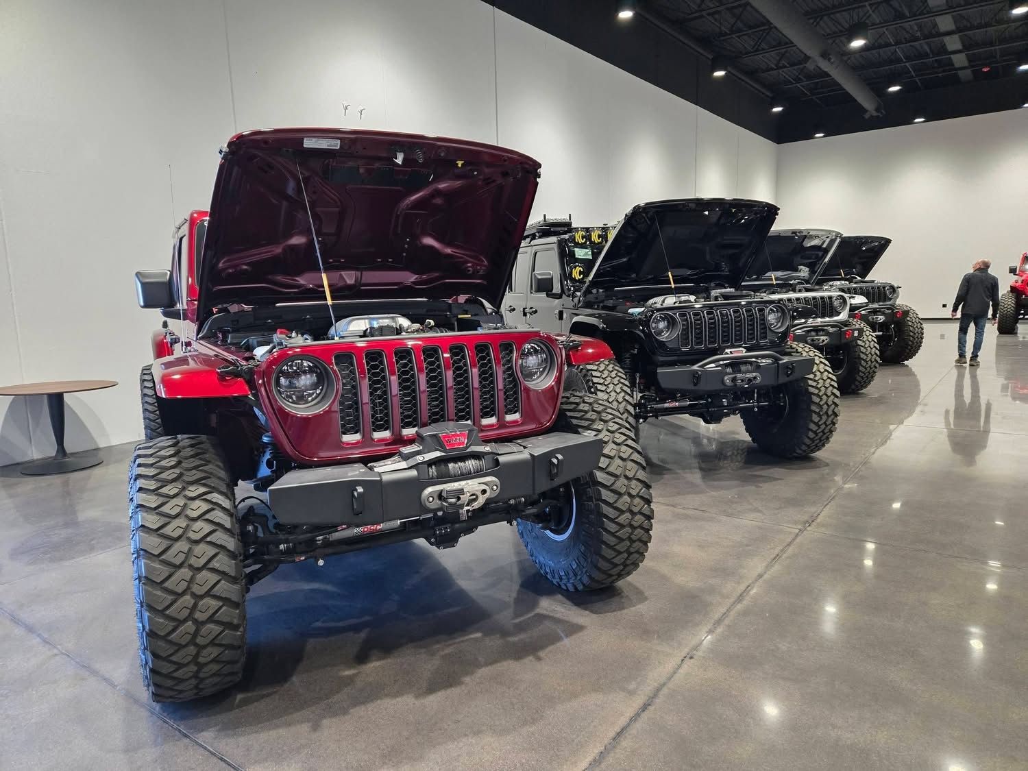 A row of custom Jeeps with hoods open in the showroom